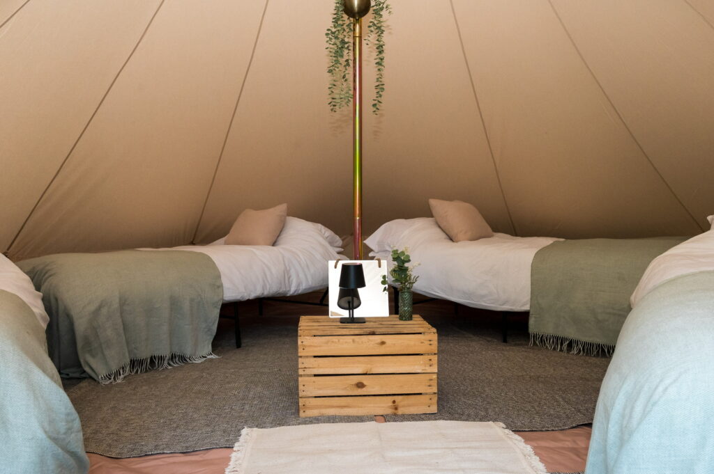 Four single beds made up inside a 5m bell tent