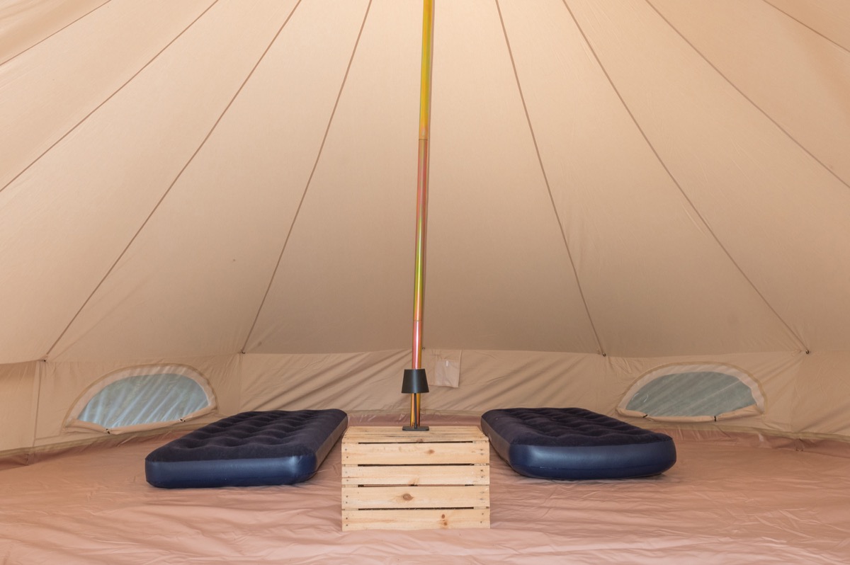 Two single airbeds laid out in a basic bell tent