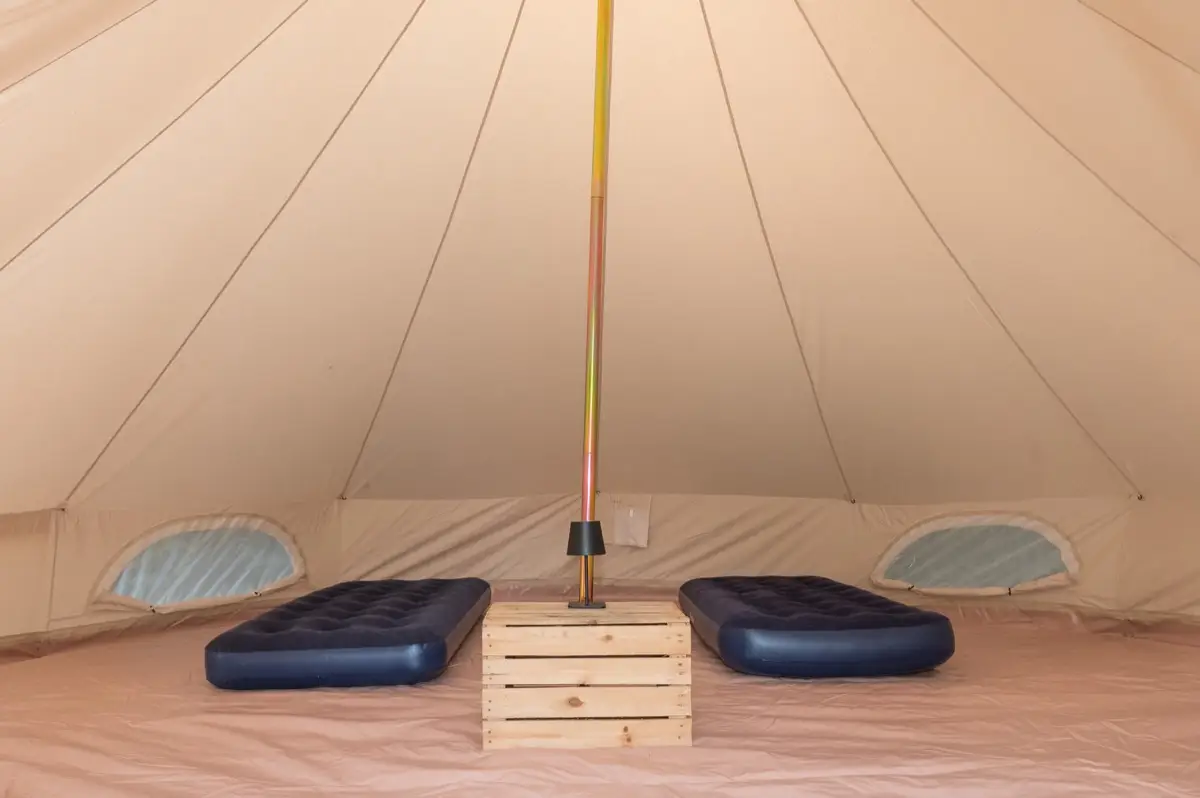 Two single beds laid out in a bell tent for a running pair