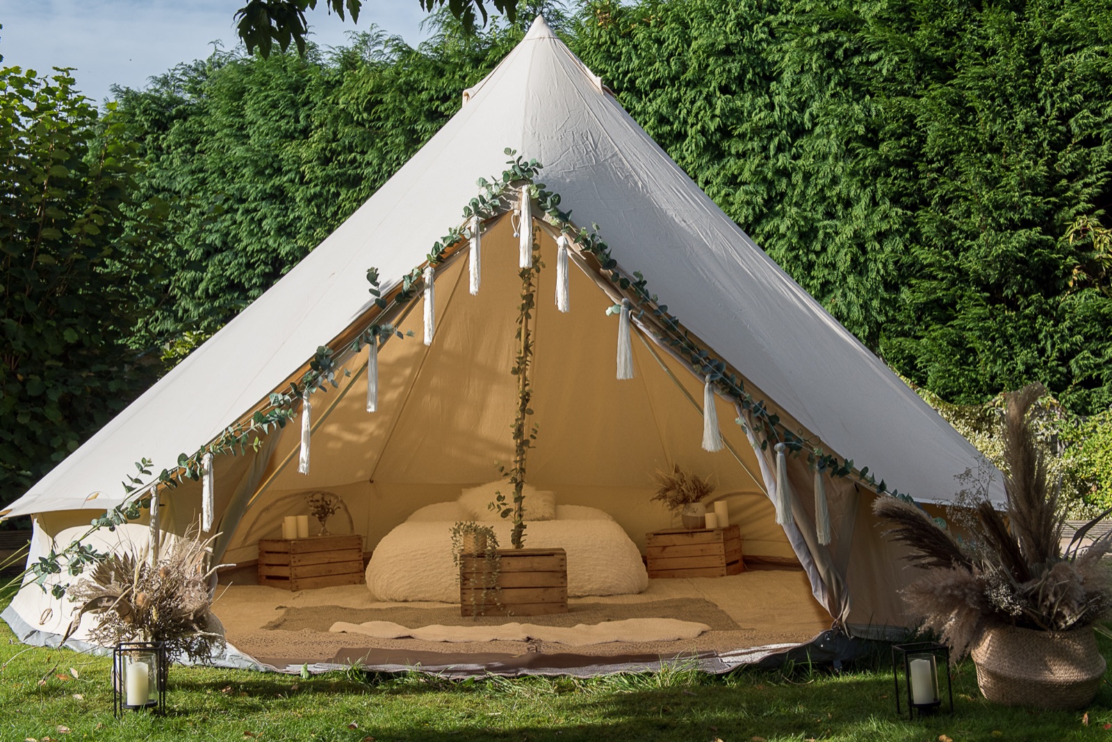 Bridal bell tent dressed with eucalyptus, ribbons and pampas, bed made up inside