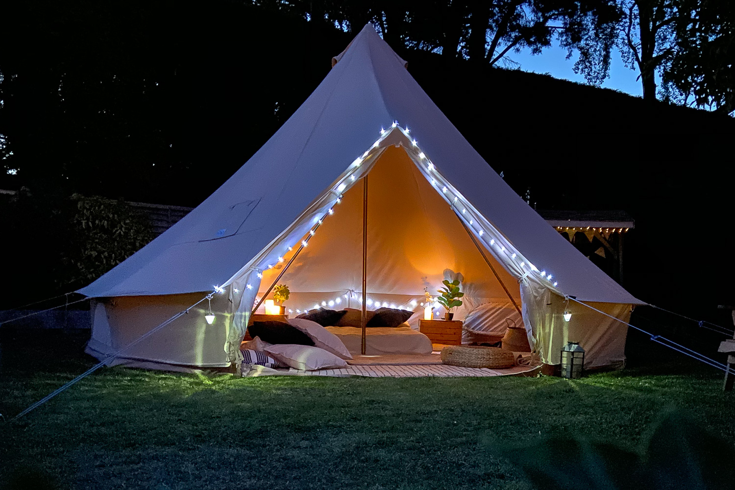 Bell tent lit up at night, beds made inside