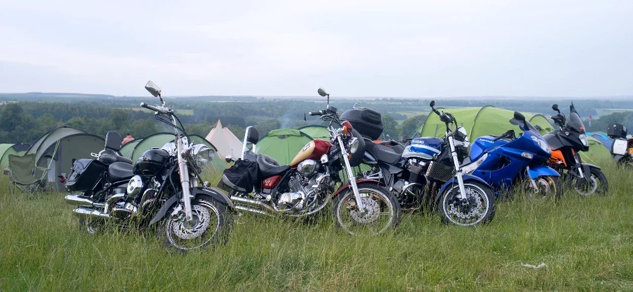 A line of bikes parked up in front of tents at the Farmyard Party, Yorkshire countryside behind