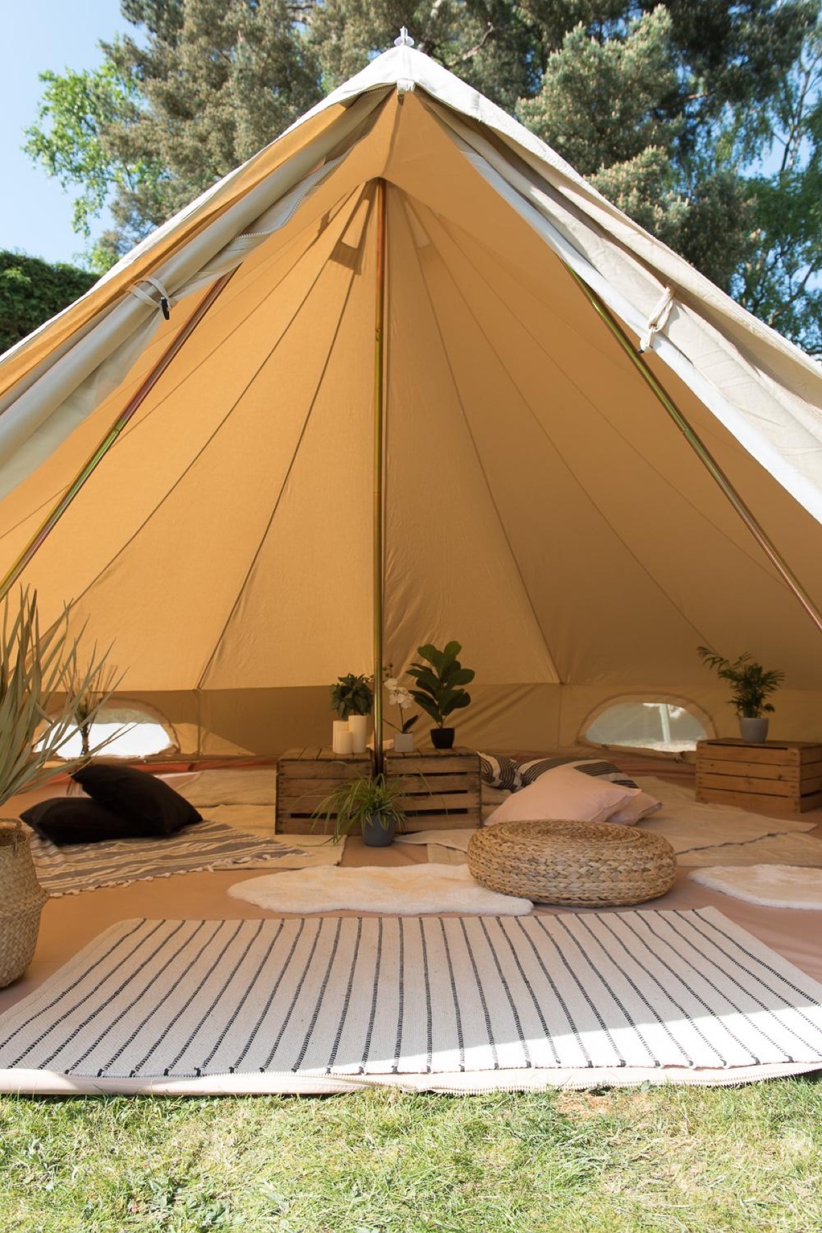 Boho-dressed bell tent open to a garden, eucalyptus garland and pampas